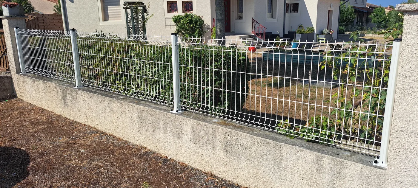 Clôture en panneaux rigides blancs posée sur un muret de façade