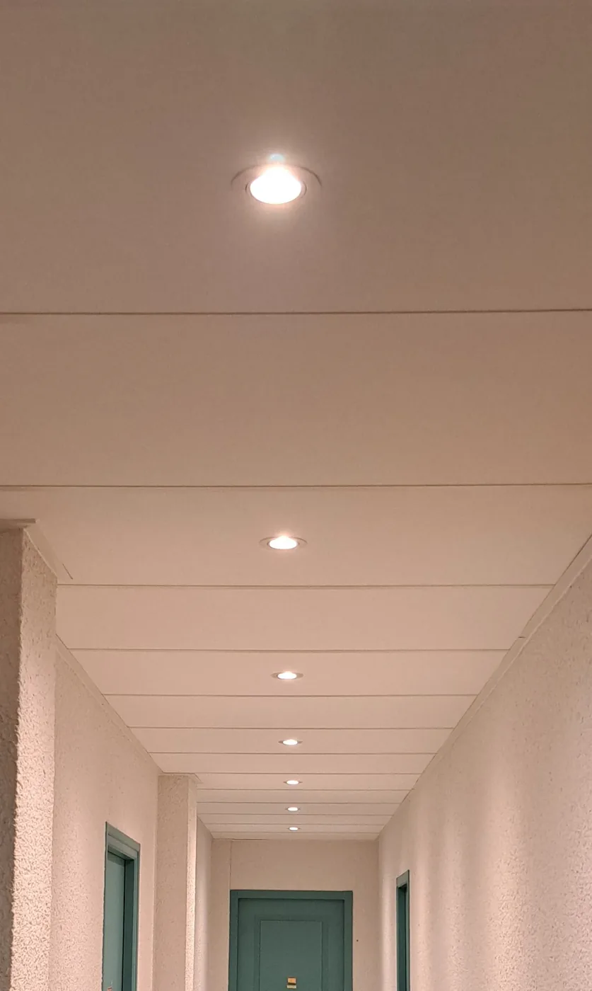 Faux plafond à lames et spots encastrés posés dans un couloir de cabinet professionnel