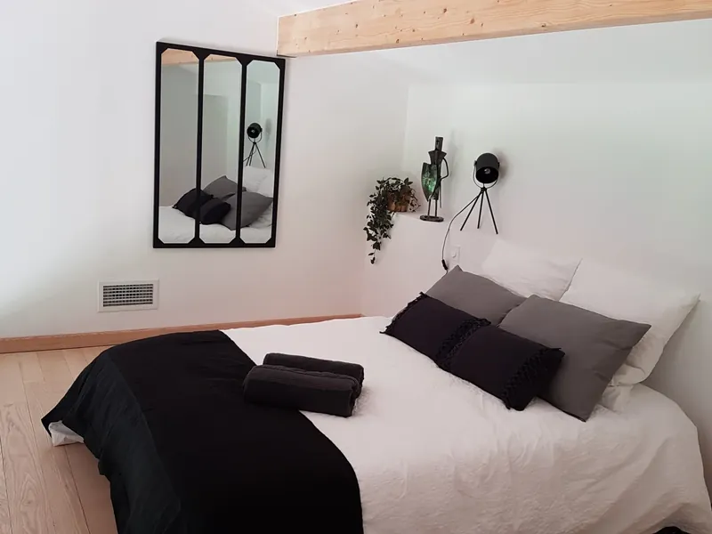 Chambre aménagée avec tête de lit bois, luminaires et verrière posés par Olivier Services