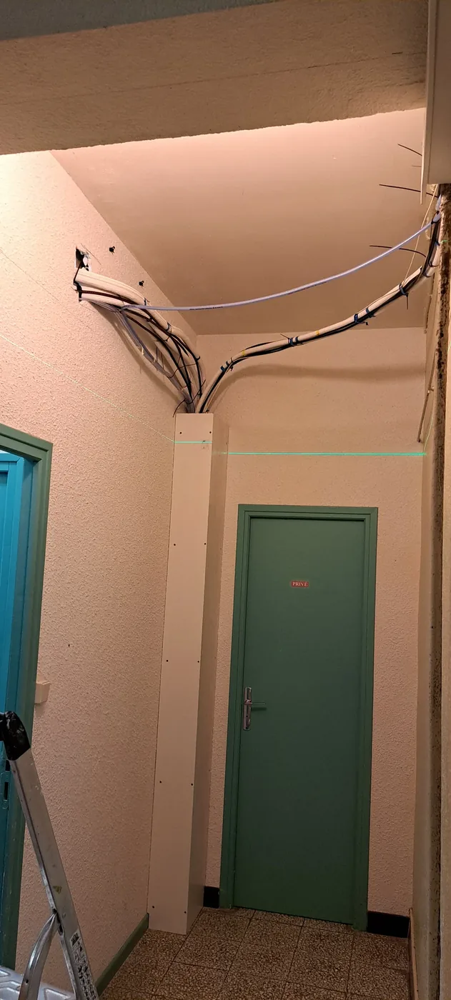 Couloir avant travaux : câbles apparents et murs à reprendre